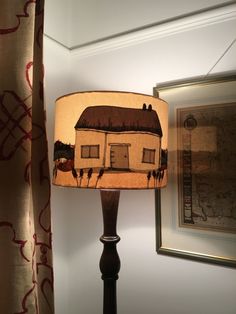 a lamp that is on top of a table next to a painting and framed pictures