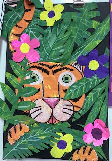 an animal made out of paper with flowers and leaves on the bottom, next to a cutout of a tiger's face