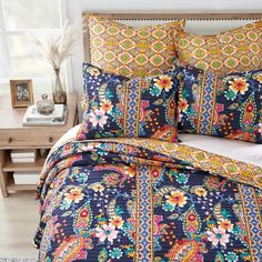 a bed covered in blue and orange floral comforters