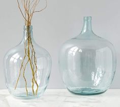 two glass vases sitting on top of a white countertop next to each other