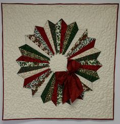 a quilted christmas wreath with red, green and white ribbons on it's center