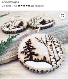 three wood slices with black and white designs on them sitting next to a tree branch