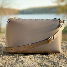 "Small crossbody bag with a zipper top to securely hold your stuff, thoughtfully crafted from super-soft and easily cleanable shimmery tan vegan leather. This handbag features an interior and exterior pocket (each sized to fit a large phone) and shoulder/crossbody strap that adjusts from to 37\" to 66\" (94 - 168 cm) to fit all body types. All Mohop handbags are handmade in our workshop in northern Illinois from animal-friendly materials and American-made hardware. 100% Vegan! Measurements: Heig Travel Crossbody Belt Bag With Zipper, Travel Belt Bag With Zipper Pouch, Outdoor Shoulder Belt Bag With Zipper Closure, Outdoor Shoulder Belt Bag With Zipper, Everyday Camera Bag With Zipper Pouch, Everyday Zipper Pouch Belt Bag, Outdoor Crossbody Bag With Removable Pouch, Rectangular Belt Bag With Zipper Pouch For Everyday Use, Modern Travel Shoulder Bag With Zipper Pouch