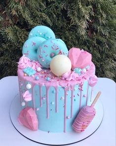 a blue cake with pink icing and sprinkles on top, sitting on a table