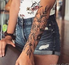 a woman's arm with flowers on it and a flower tattoo on her left arm