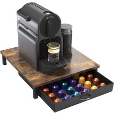 an espresso machine is sitting on top of a drawer with colorful cups in it