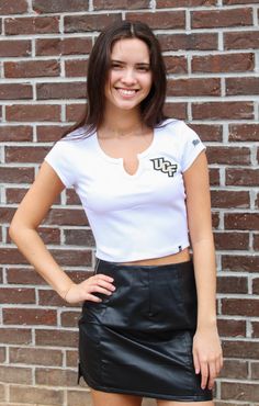 Shopping for cute game day gear? We've got you covered! The UCF Cropped Cali Tee is the perfect addition to your closet. This top features a scoop v-neckline and ribbed material for a comfortable and flattering fit. The school logo on the front gives this tee a sleek and spirited look. Whether heading to class or a tailgate, this top is a must-have! Pair with a cute skirt or shorts for the perfect look! Details: *OFFICIALLY LICENSED* True to size Stretchy Ribbed Material Scoop V-Neckline 95% cot Sporty V-neck Top For College, Casual Fitted T-shirt For Game Day, Casual V-neck Top For College, Stretch V-neck Top For Streetwear, V-neck Spring College Tops, White V-neck Top For College, Collegiate Style Fitted Tops For Spring, Casual V-neck T-shirt For College, Varsity Fitted Top For Game Day