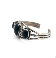 Vintage Sterling Silver Black Onyx Cuff Bracelet - The cuff bracelet features three pieces of striking black onyx and is adorned with expertly-crafted silverwork. The triple wire shank provides both comfort and durability. This well-made Southwest piece is substantial and built to withstand the test of time. Black Onyx Size: S/M 7" Cuff includes 1" Gap Inner circumference 7" total Stone (center): 1"L x .75"W Metal: Sterling Silver Weight: 33.5 Grams This listing is for (1) Cuff only Explore our curated selection of exceptional Vintage Bracelets here. Discover the entire 'Silver Raven' Vintage Collection for yourself. Classic Black Cuff Bracelet Bangle, Classic Black Cuff Bracelet In Bangle Style, Adjustable Black Sterling Silver Cuff Bracelet, Black Polished Cuff Bracelet For Formal Occasions, Formal Black Cuff Bracelet With Polished Finish, Formal Black Polished Cuff Bracelet, Adjustable Black Cuff Bracelet With Polished Finish, Raven Jewelry, Silver Work