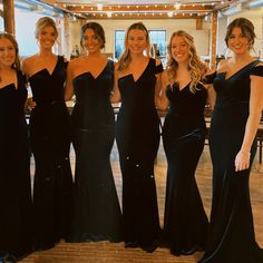 four beautiful women in long dresses posing for a photo at a formal event with each other