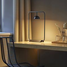 a table with a lamp and a bottle on it next to a window sill