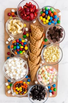 an ice cream cone surrounded by candy and candies on a cutting board with bowls