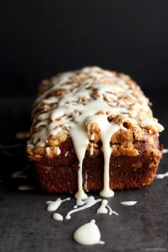 a loaf of bread covered in icing on top of a black tablecloth with white sprinkles