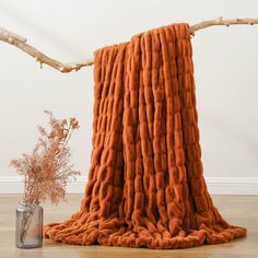 a pile of orange yarn sitting on top of a wooden floor next to a vase