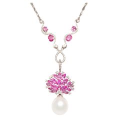 The pink sapphire diamond and South Sea pearl pendant features a spray of marquise shape faceted sapphires spangled with round diamonds. The jewel suspends a splendid South Sea pearl of extraordinary size: 20 x 18mm. The 2” pendant is accompanied by a 16” chain decorated with oval cut pink sapphire motifs. The total weight of sapphire is 19.90 carats; the total diamond weight is 2.32. The pendant is detachable, allowing for versatile use. All of our pearls are untreated: their natural color and