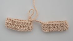 two crocheted pieces of yarn tied together on a white surface, with one knot in the middle