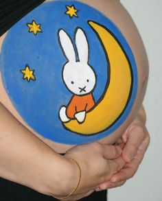 a pregnant woman holding her belly painted with the image of a rabbit on it