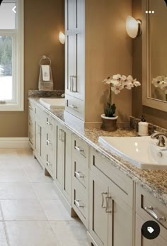 a bathroom with double sinks and two mirrors on the wall, along with marble counter tops