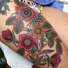 a woman's thigh with flowers and leaves on it