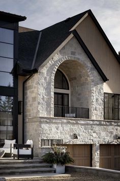 a stone house with two garages and stairs leading up to the second story area