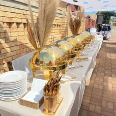 there is a long table with plates and silverware on it that has gold decorations