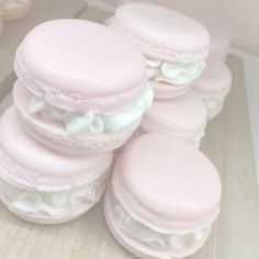 a pile of pink macaroons sitting on top of a wooden table next to each other