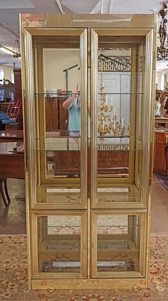 an antique china cabinet with glass doors and gold trimmings, in the middle of a living room