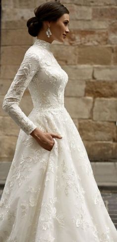 a woman in a white wedding dress is standing on the street with her hand on her hip