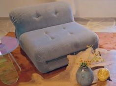 a blue couch sitting on top of a wooden table next to a vase filled with flowers