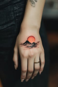 a woman's hand with a mountain tattoo on it