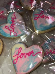 some heart shaped cookies with pink and blue icing on top of plastic wrappers