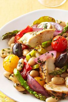 a white plate topped with chicken, asparagus, tomatoes and other veggies