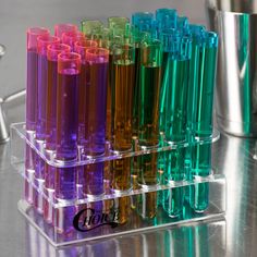 several different colored tubes in a clear holder on a table next to a silver cup