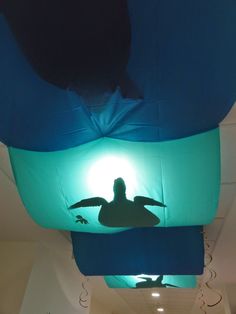 the silhouette of a sea turtle is projected on an inflatable light above a hallway