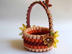 a small basket with beads and flowers on the inside is sitting on a white surface