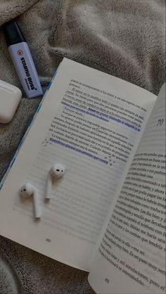 an open book with earbuds laying on top of it