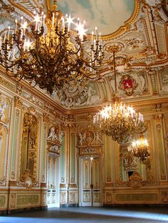 an ornate room with chandeliers and paintings on the walls, painted in gold