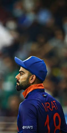 a man with a beard wearing a blue hat and an orange necktie stands in front of a crowd