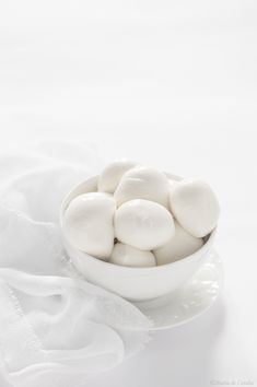 a white bowl filled with marshmallows sitting on top of a white cloth