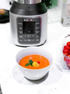 a bowl of tomato soup next to an instant pot of cranberries and cherries