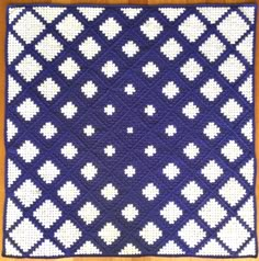 a blue and white crocheted blanket on top of a wooden table