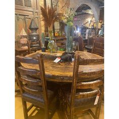 a wooden table surrounded by chairs and vases with plants on them in a store