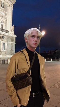 a man with blonde hair standing in front of a building