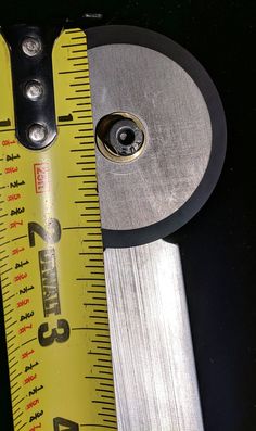 a measuring tape and a metal tool on a table