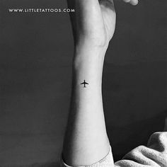 a small tattoo on the wrist of a person with an airplane in the sky above them