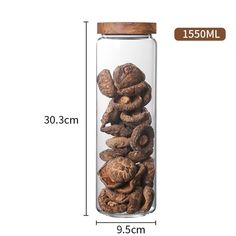 a glass jar filled with walnuts on top of a white table next to a measuring ruler