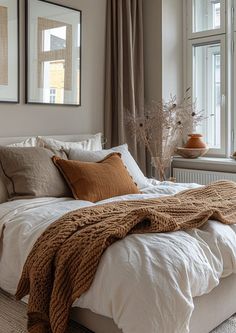 a bed with white linens and brown pillows