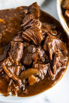 a white plate topped with meat covered in gravy