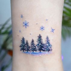 snowflakes and pine trees on the side of a woman's ankle tattoo