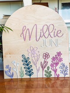 a wooden sign with flowers and the words mile june painted on it's side