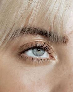 a woman's eye with blonde hair and blue eyeshade, close up